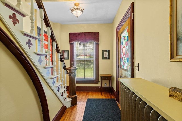 hallway featuring stairway, wood-type flooring, and baseboards