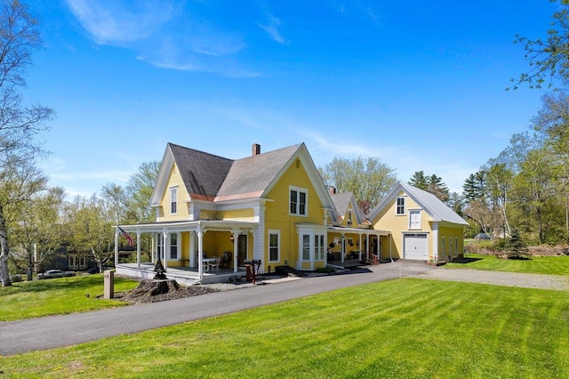 view of front of house featuring covered porch, driveway, a front lawn, and a chimney