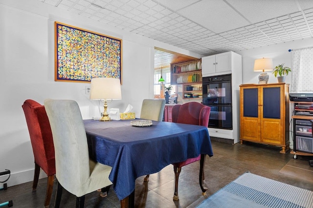 dining room with a paneled ceiling and dark wood-style floors