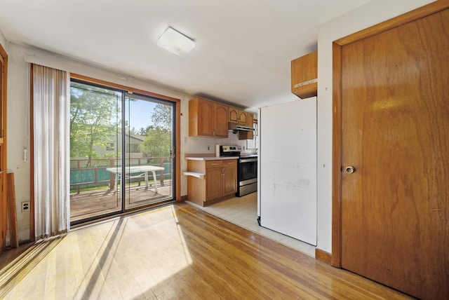 kitchen with stainless steel range with electric cooktop, light wood-type flooring, light countertops, and brown cabinets