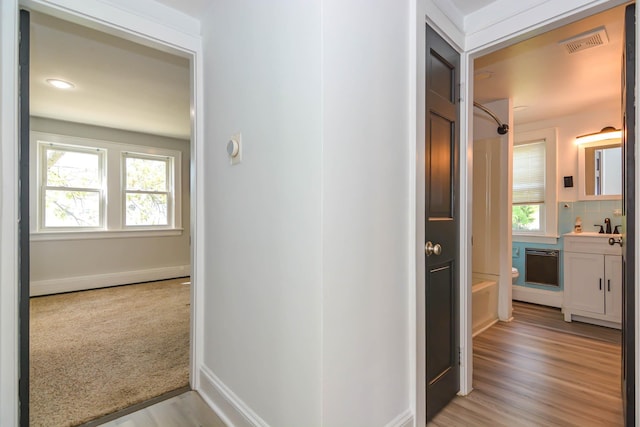 hall with a sink, baseboards, light wood-style floors, and recessed lighting