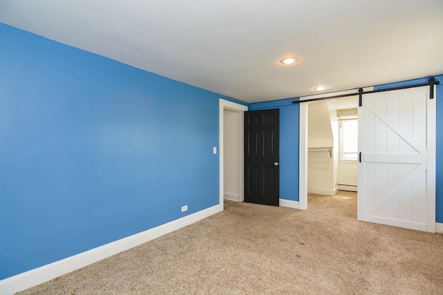 unfurnished bedroom with a baseboard heating unit, carpet flooring, baseboards, recessed lighting, and a spacious closet