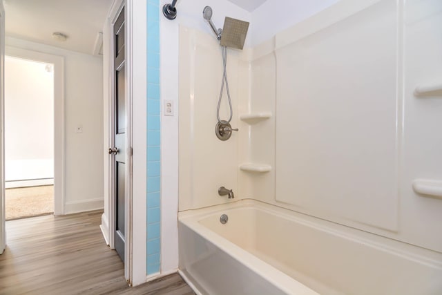 bathroom with wood finished floors,  shower combination, baseboard heating, and baseboards