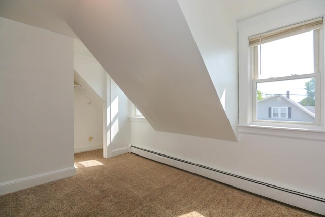 additional living space featuring baseboard heating, light colored carpet, and baseboards