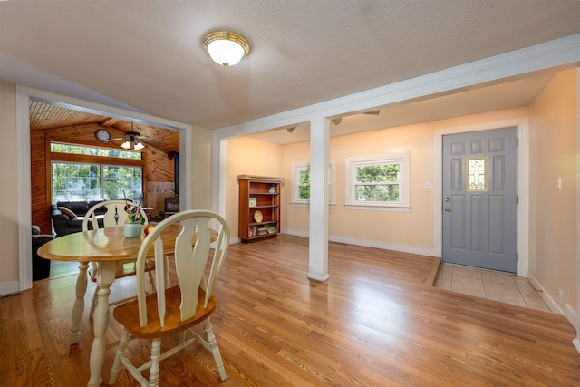 dining area featuring light wood-style flooring, baseboards, and vaulted ceiling