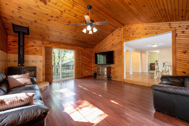 living area featuring wood walls, a wood stove, hardwood / wood-style flooring, and ceiling fan