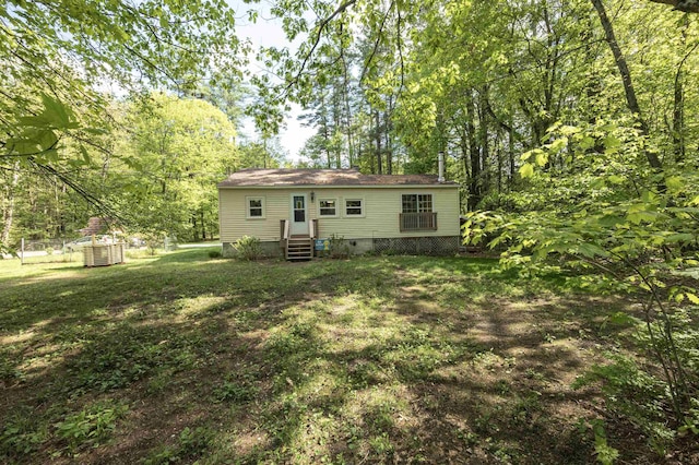 rear view of house featuring entry steps, crawl space, and a lawn