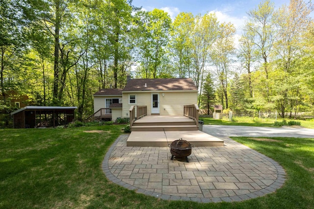back of house featuring a fire pit, a yard, a deck, and a patio area