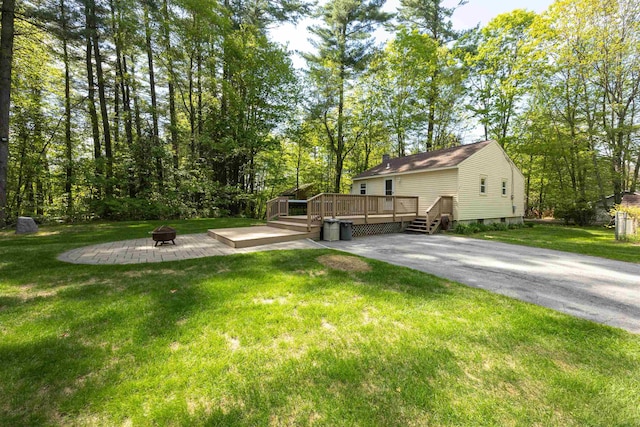 view of green lawn with a fire pit and a deck
