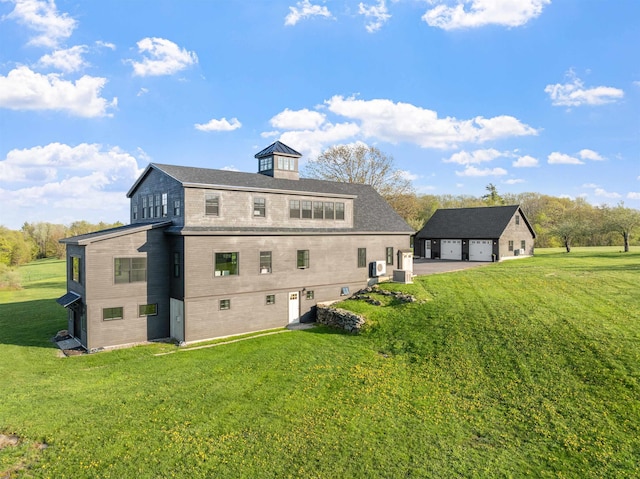 back of house with a lawn, a garage, an outdoor structure, and driveway