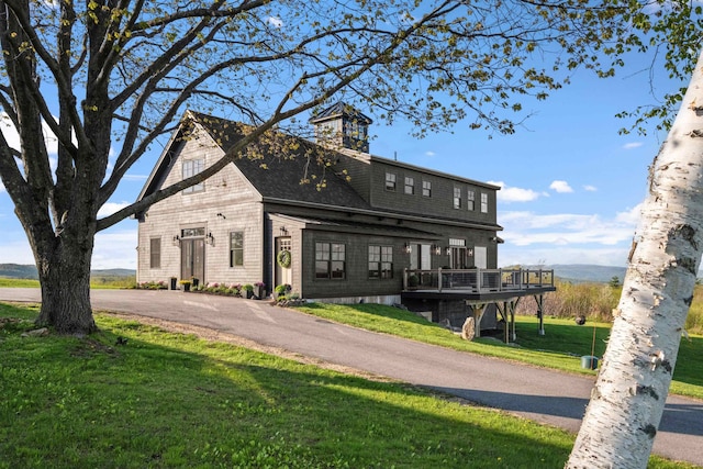 view of front of property featuring a front lawn, a shingled roof, and a wooden deck