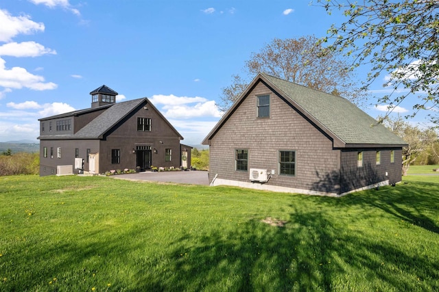 rear view of property with a lawn and roof with shingles