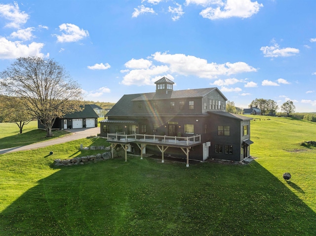 rear view of house featuring a wooden deck, driveway, and a yard