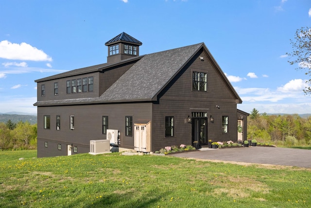 view of front facade featuring a front yard and a shingled roof