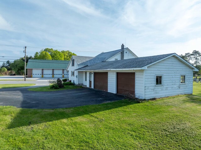 3005 Vt 78 Rte, Highgate, VT 05459 - view of side of home featuring an attached garage, asphalt driveway, a shingled roof, and a lawn