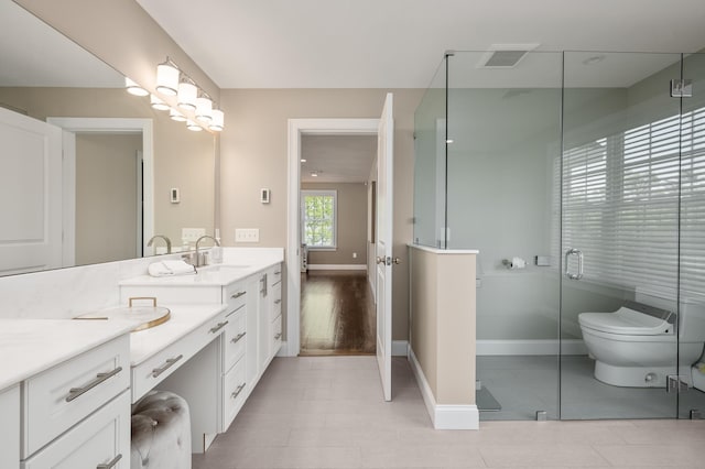full bath with vanity, baseboards, a shower stall, and toilet