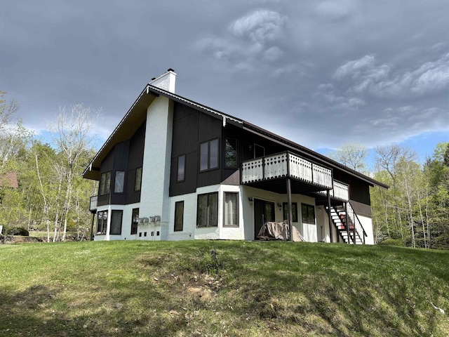 rear view of house featuring a lawn, a chimney, a deck, and stairs