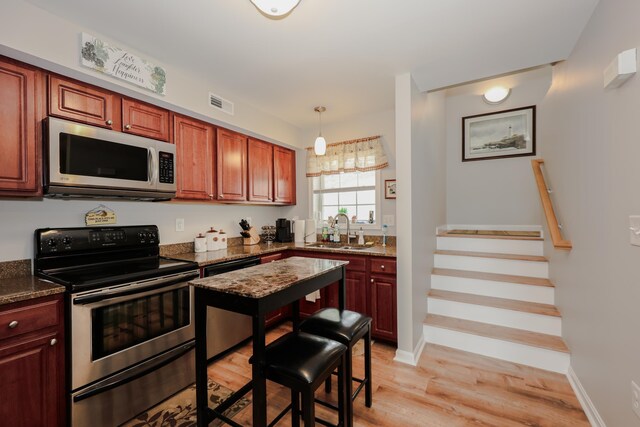 11 Sullivan Way Unit 6, Laconia, NH 03246 - kitchen with stainless steel appliances, a sink, light wood-style flooring, dark stone countertops, and baseboards