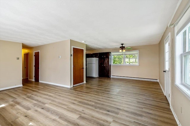 2099 W Shore Rd, Alburgh, VT 05440 - unfurnished living room featuring a baseboard heating unit, a ceiling fan, wood finished floors, and baseboards