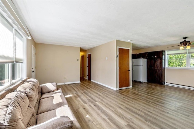 2099 W Shore Rd, Alburgh, VT 05440 - living room with light wood-type flooring, baseboards, ceiling fan, baseboard heating, and a textured ceiling