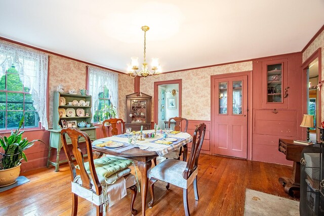 685 Abbot Hill Rd, Wilton, NH 03086 - dining area featuring wallpapered walls, a chandelier, wood-type flooring, ornamental molding, and a wainscoted wall