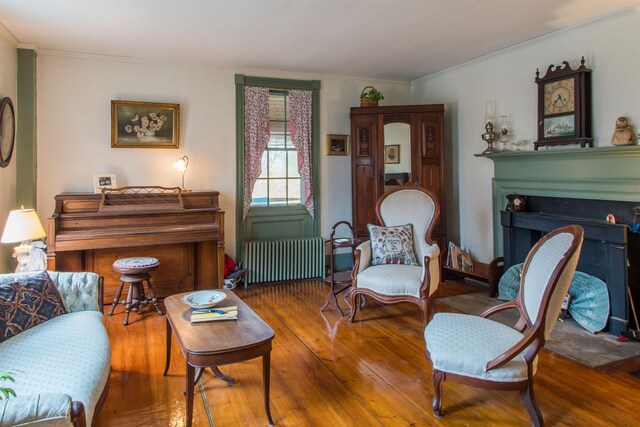 685 Abbot Hill Rd, Wilton, NH 03086 - living room featuring radiator heating unit, hardwood / wood-style floors, crown molding, and a fireplace with flush hearth
