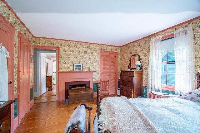 685 Abbot Hill Rd, Wilton, NH 03086 - bedroom with light wood finished floors, wallpapered walls, ornamental molding, a closet, and a fireplace