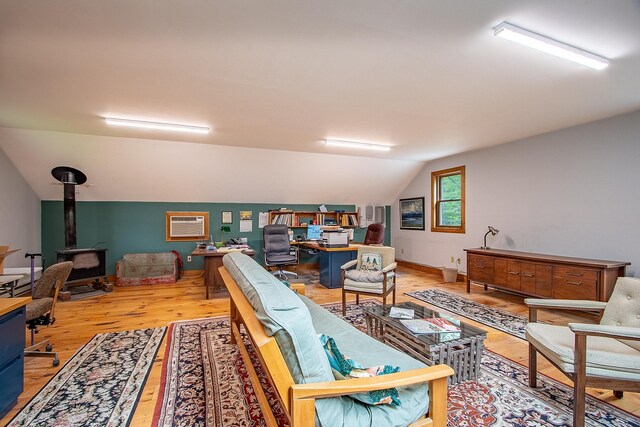 685 Abbot Hill Rd, Wilton, NH 03086 - living room with a wood stove, wood finished floors, a desk, vaulted ceiling, and an AC wall unit