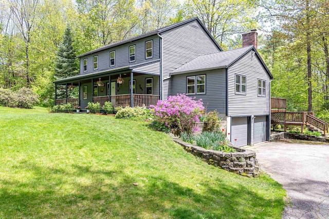 view of front facade with a chimney, driveway, a garage, a porch, and a front lawn