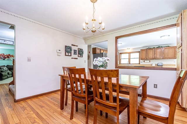 dining area featuring a chandelier, light wood finished floors, and baseboards