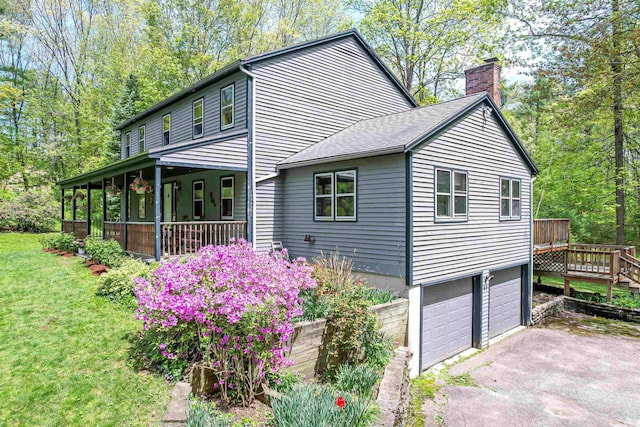 view of home's exterior featuring a chimney, a garage, driveway, a porch, and a yard