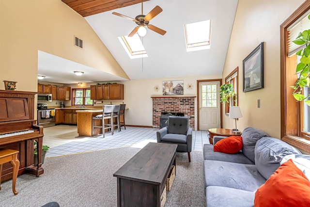 living room with a skylight, healthy amount of natural light, ceiling fan, high vaulted ceiling, and a fireplace