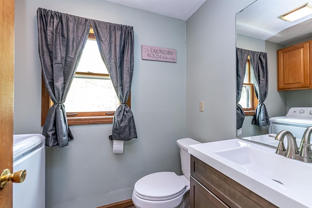 bathroom with washer and clothes dryer, toilet, vanity, and a textured ceiling