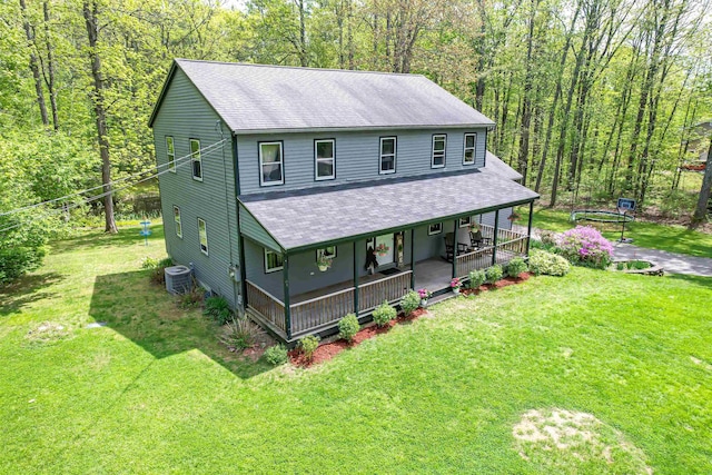 farmhouse with roof with shingles, covered porch, central air condition unit, and a front lawn