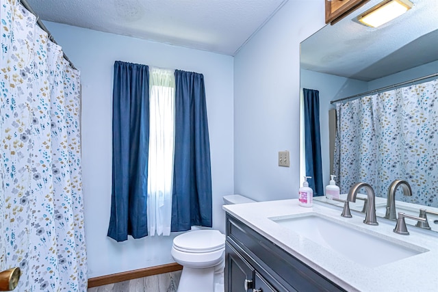 full bathroom featuring toilet, wood finished floors, vanity, a shower with curtain, and a textured ceiling