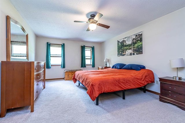 carpeted bedroom with a textured ceiling, baseboards, and a ceiling fan