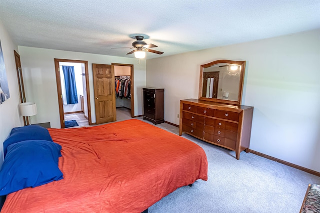 carpeted bedroom with baseboards, a walk in closet, a closet, connected bathroom, and a ceiling fan