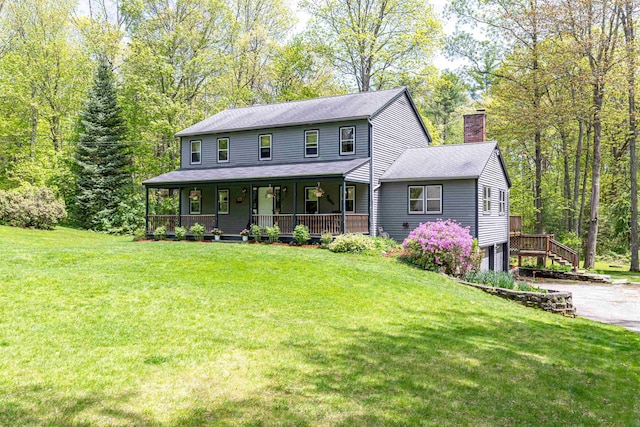 view of front of property featuring a chimney, covered porch, a garage, and a front lawn