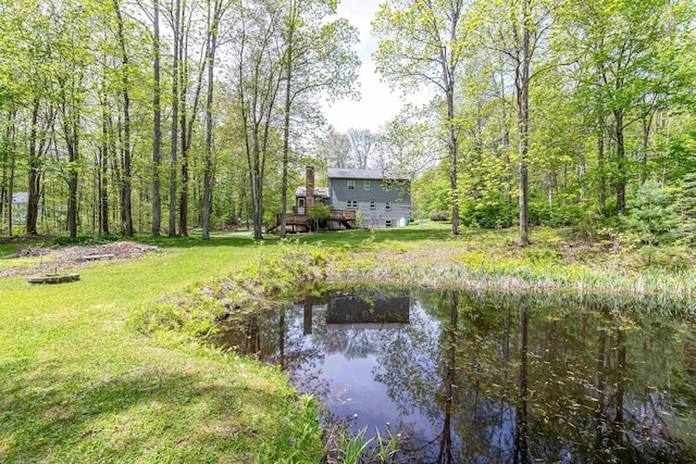 view of grassy yard with a deck with water view