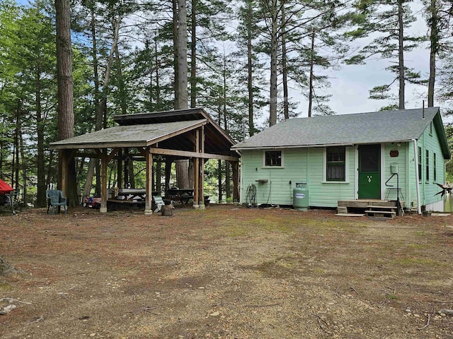 back of property with a gazebo and roof with shingles