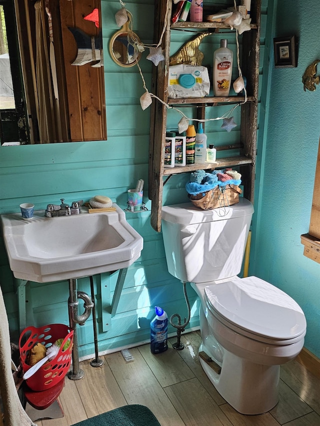 bathroom featuring wood finished floors, toilet, and a sink