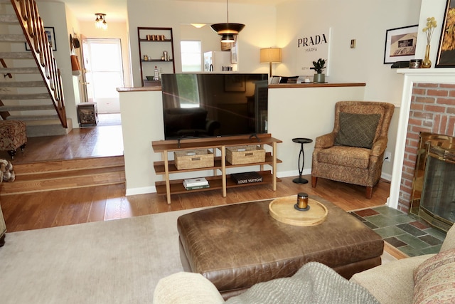 living room with a fireplace, wood finished floors, stairway, and baseboards
