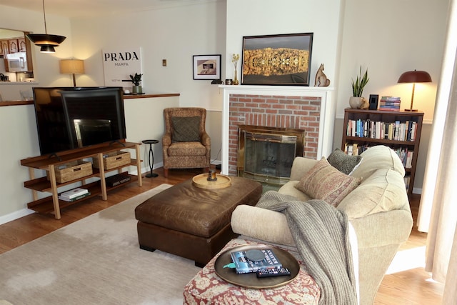 living area with wood finished floors, a fireplace, and baseboards