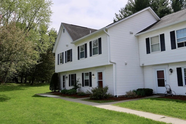colonial inspired home featuring a front yard and a shingled roof