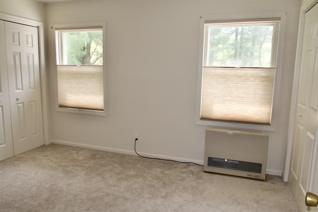 unfurnished bedroom with heating unit, carpet flooring, baseboards, and a closet