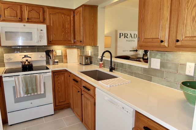 kitchen with white appliances, a sink, decorative backsplash, and light countertops