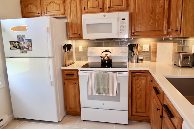 kitchen featuring white appliances, light countertops, light tile patterned floors, and baseboard heating