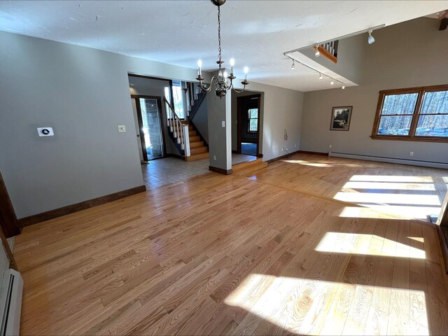 80 Mill St, Conway, NH 03813 - unfurnished living room featuring a baseboard radiator, a chandelier, and plenty of natural light