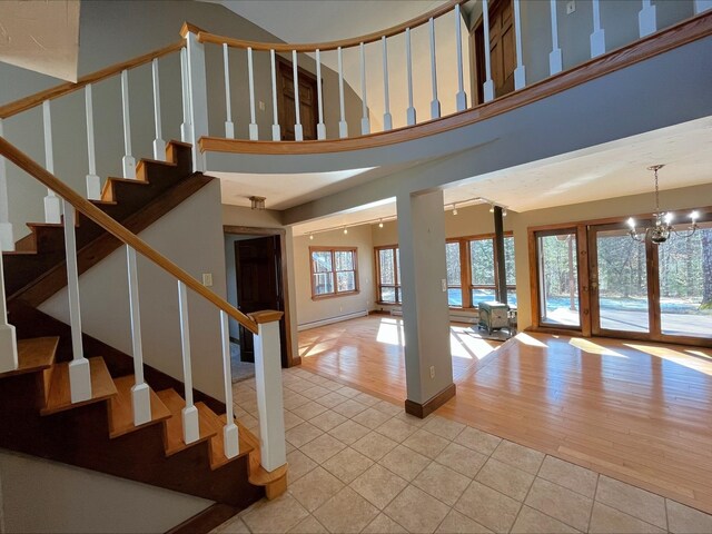 80 Mill St, Conway, NH 03813 - stairway featuring tile patterned floors, baseboard heating, a chandelier, and a towering ceiling