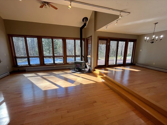 80 Mill St, Conway, NH 03813 - unfurnished living room featuring rail lighting, a wood stove, a chandelier, baseboard heating, and hardwood / wood-style floors